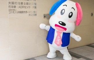 大阪府行政書士会館の看板の前に立つさぽ太